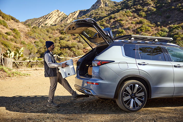 A man carrying cargo using the Hands-Free Power Liftgate in the Outlander PHEV