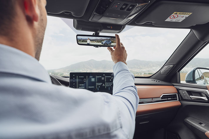 A hand adjusting the frameless digital rearview mirror in the Outlander PHEV